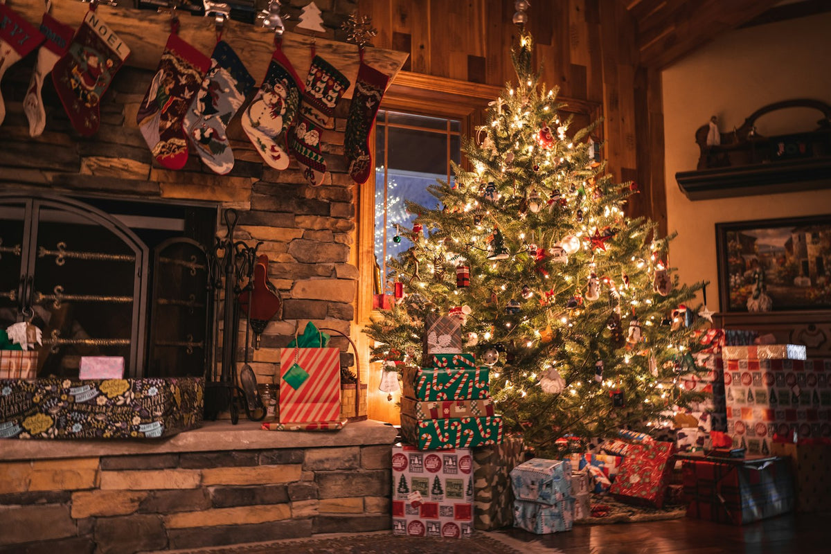 Sapin de Noël illuminé et cadeaux près de la cheminée