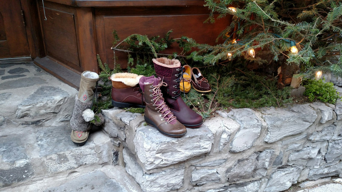 Winterstiefel im Schnee vor einer Haustür mit Tannengrün