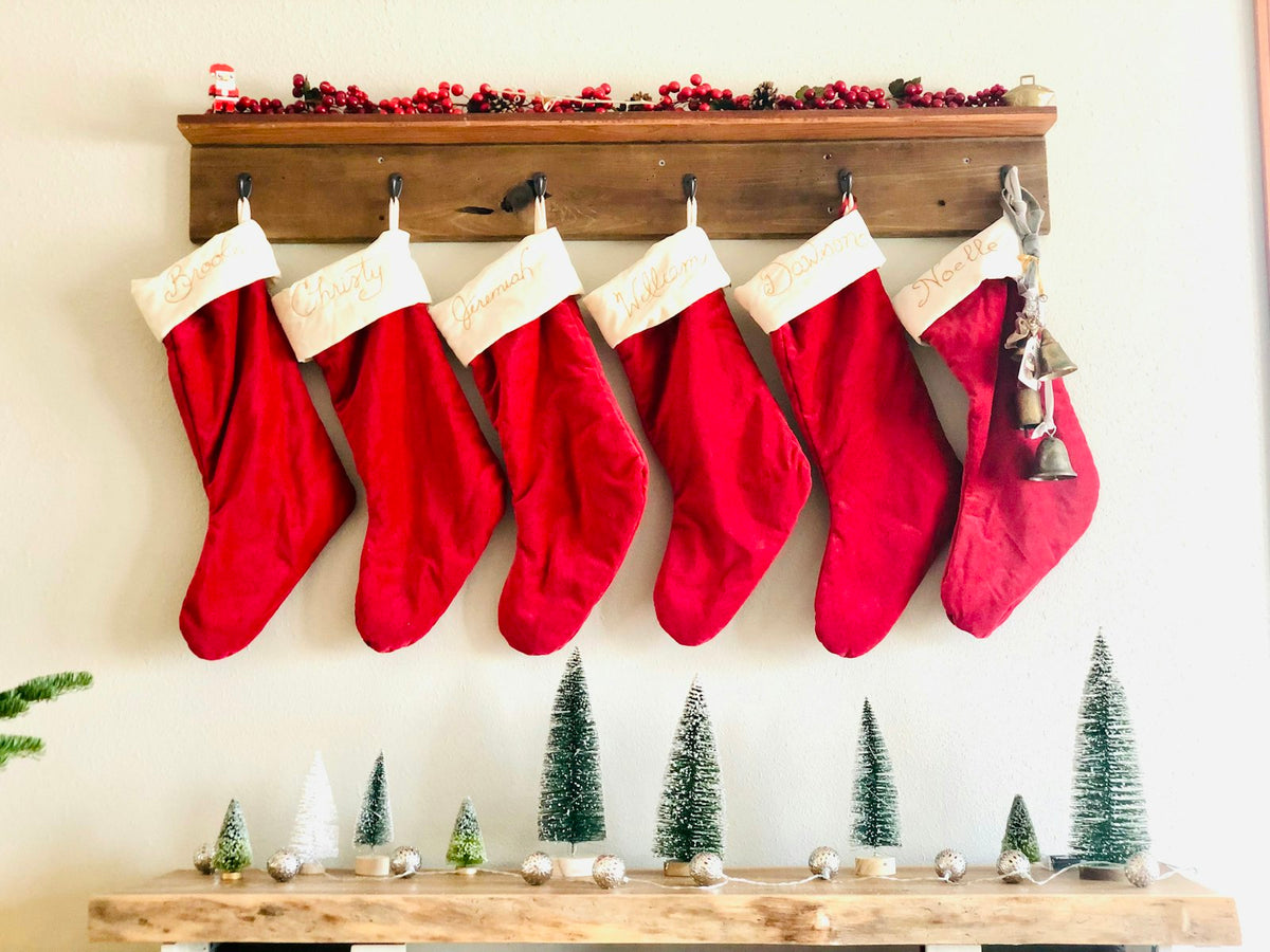 Rote Nikolausstrümpfe hängen in einer Reihe vor weihnachtlicher Deko