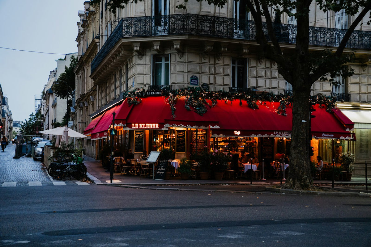 Café parisien décoré pour Noël avec son auvent rouge au coin d'une rue