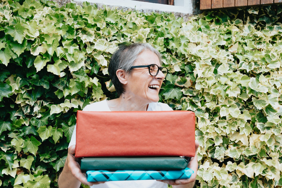 Femme souriante qui tient une pile de cadeaux